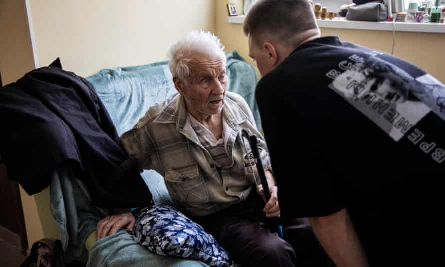 Andriy Kit assists Anatoliy Savelevych, who arrived at the shelter for displaced people set up inside a factory in Dnipro, Ukraine.