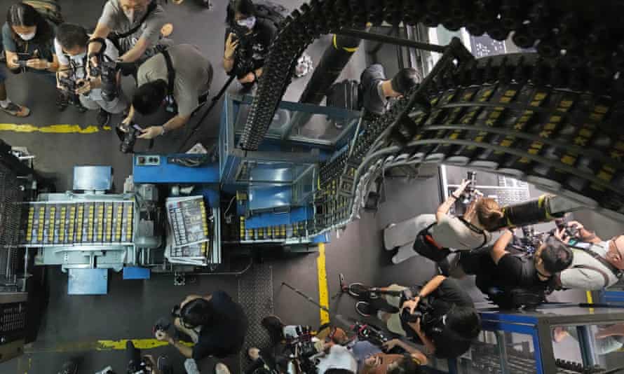 Photographers take photos of copies of Apple Daily coming off the printing press on Friday.