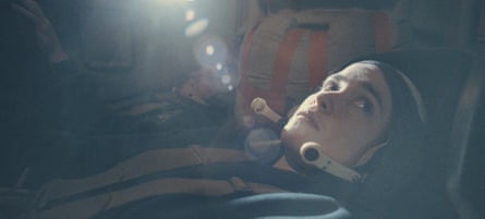An astronaut lying down in the module.