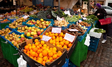 A woman buying food from a greengrocer stall