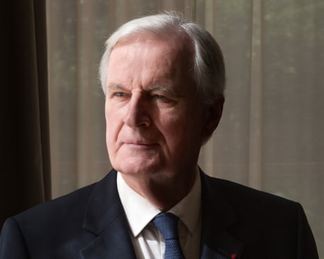 Michel Barnier, an older man with grey hair wearing a dark suit and blue tie in an indoor setting
