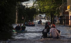 Small boats carry people up and down a flooded street