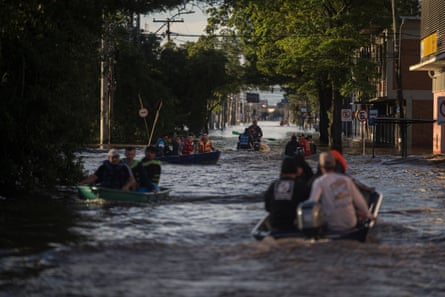 People in several boats on flood waters in a main street