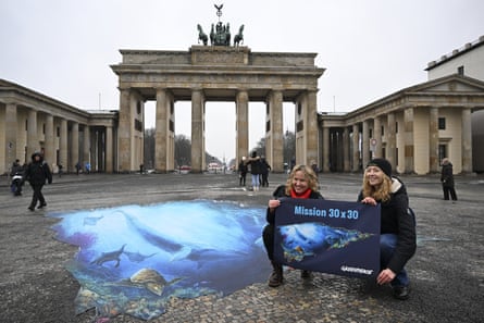 Activists kneel next to painting of the sea on the pavement