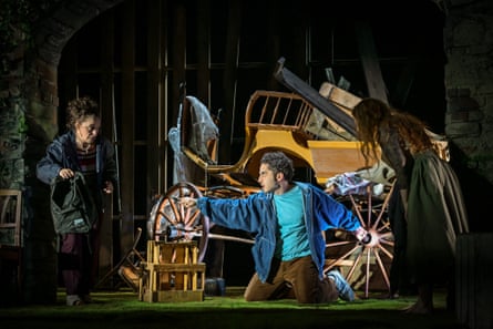 In Refuge, a kneeling man gestures dramatically while two women watch nearby, among stage debris