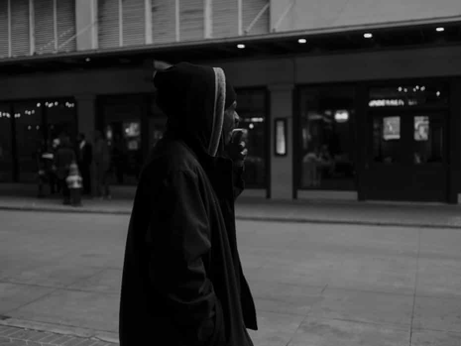 Man in a hoodie smoking outside
