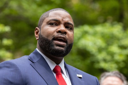 Young middle-aged Black man with trim hair and beard in blue suit and red tie.