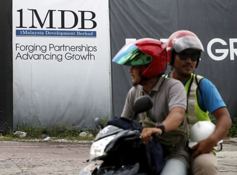 Motorcyclists pass a 1Malaysia Development Berhad (1MDB) billboard at the Tun Razak Exchange development in Kuala Lumpur, Malaysia, February 3, 2016.