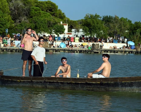Some people aboard a boat get ready to observe the total solar eclipse at La Albufera coastal lagoon in Valencia, Spain.