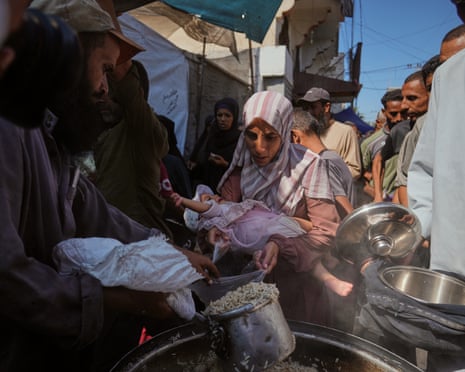 Palestinians receive donated food at a community kitchen in Deir al-Balah, central Gaza Strip, Thursday, 16 October 2025.