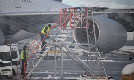 Workers clear a towable passenger staircase from snow as Munich airport has cancelled all incoming and outgoing flights until noon due to a forecast for sleet in the region