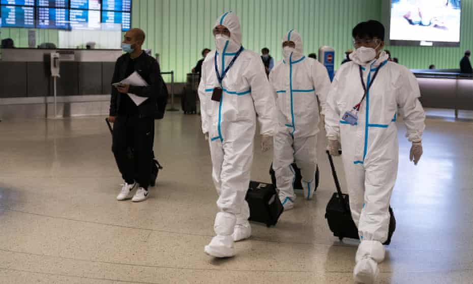 Air China flight crew members in hazmat suits at Los Angeles airport on Tuesday amid concerns about the new Covid strain, Omicron.
