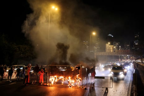 Fire blazes with the words in Hebrew, ‘Enough with the madness’, as demonstrators and relatives of hostages block a road in Tel Aviv, demanding the immediate release of hostages kidnapped by Hamas, on Wednesday evening.