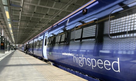 Shot down a platform of a rake of sleek modern dark blue carriages with paler doors, bearing the logo 'Southeastern highspeed'