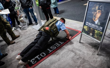 A visitor wearing a tactical vest does push ups at a Bundeswehr stand at the Gruene Woche International Agricultural Fair in Berlin.