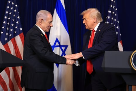 Donald Trump and Benjamin Netanyahu shake hands in front of American and Israeli flags