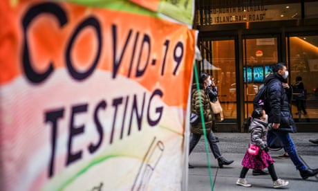 People wearing masks pass by a Covid testing site in New York City on 12 December.