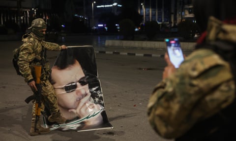 A Syrian opposition fighter takes a picture of a fellow rebel stepping on a portrait of Bashar al-Assad in Aleppo
