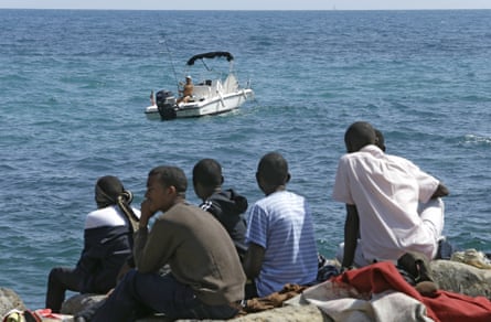 Migrants looks at a fisherman as they sit at the Franco-Italian border near Menton, south-eastern France.