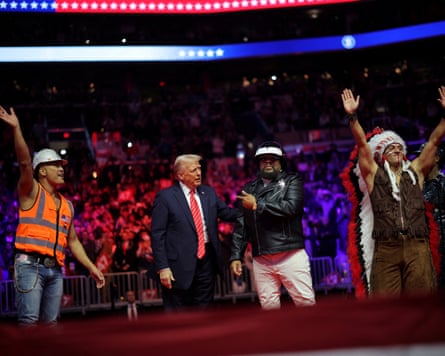 Trump on stage with the band, with US flag colours behind them