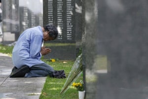 a person kneels in front of a memorial