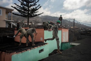 Members of the Spanish army remove ashes from houses covered with lava in Las Manchas