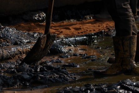 A fisher puts down a shovel of crude oil as he cleans the shore of Maracaibo Lake.