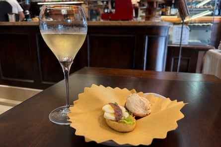 A glass of white wine on a table with egg-and-anchovy and baccalà mantecato tartine at Caffè Monte Baldo.