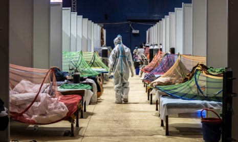  A medical worker observes patients who have been infected by Covid-19 inside a makeshift are facility in a sports stadium in New Delhi on 2 May 2021.