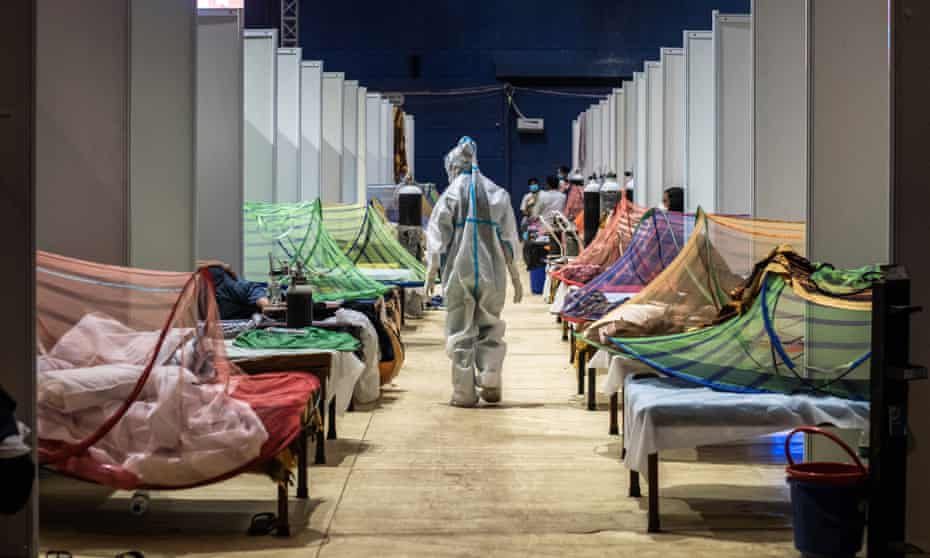 A medical worker observes patients who have been infected by Covid-19 inside a makeshift are facility in a sports stadium in New Delhi on 2 May 2021.