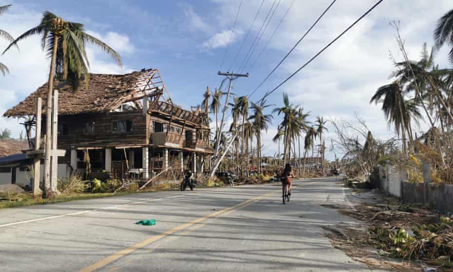 A cyclist travels past destroyed vegetation and houses along a road in Dapa town, Siargao island on December 21, 2021, days after super Typhoon Rai devastated the island.