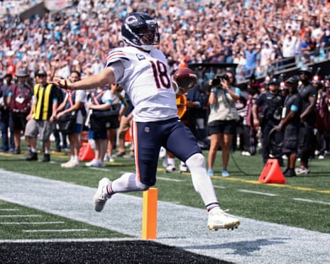 Caleb Williams leaps into the end zone holding the ball to score a touchdown