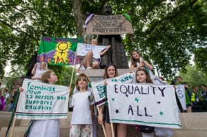 A group of girls pose for photographs for their mothers next to a statue of Millicent Fawcett in Parliament Square in London