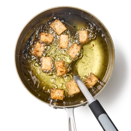 Tofu getting fried in a frying pan