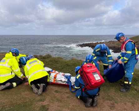 Coastguards rescue officers on a cliff with a patient on backboard