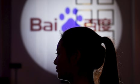 A woman is silhouetted against the Baidu logo at a new product launch from Baidu, in Shanghai, China, November 26, 2015. 
