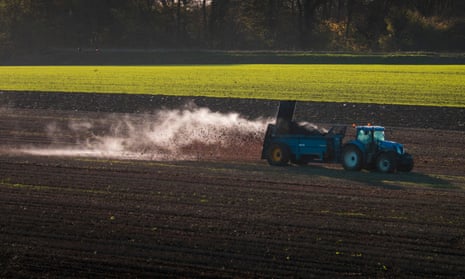 A tractor in a field spreading manure.