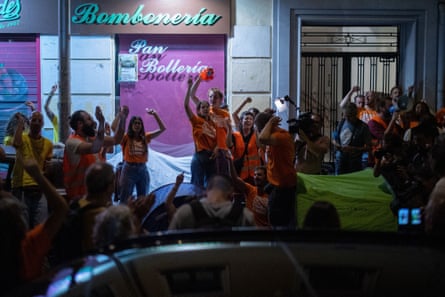 People wearing orange T-shirts raise their arms in protest on a city street