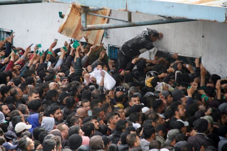 Palestinians gather to receive aid outside an UNRWA warehouse in Gaza City on Monday 18 March.