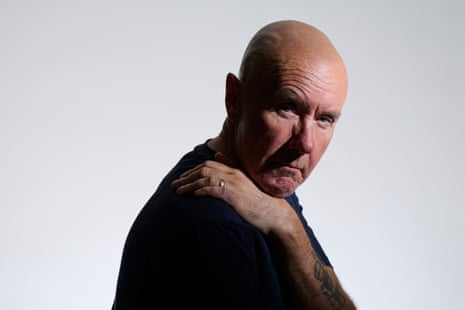 A bald-headed man wearing a black top, looking scarily into the camera