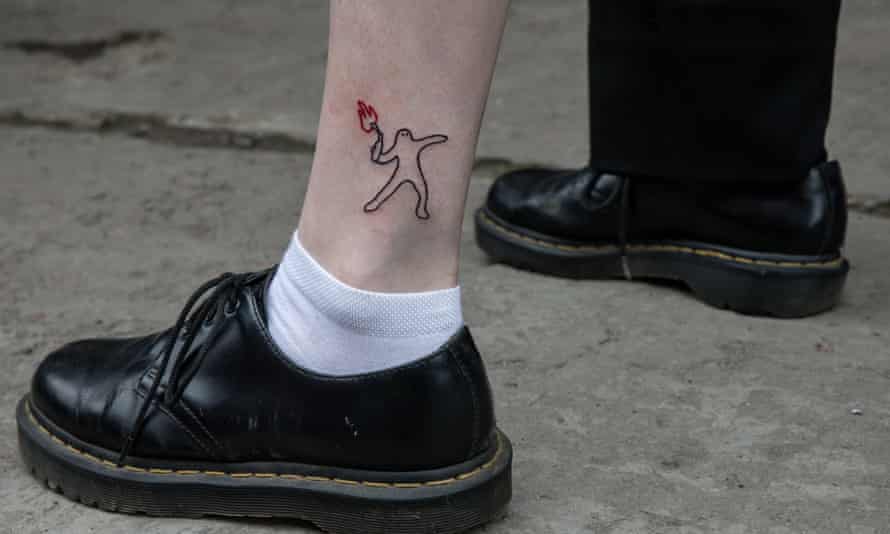 A young girl in Kyiv sports a tattoo on her ankle of a man throwing a Molotov cocktail with an stylised Ukraine coat of arms as a flame.