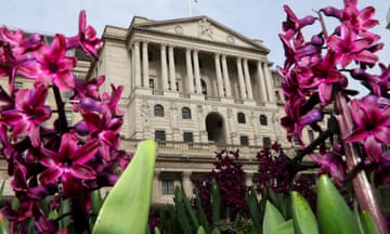 Purple and magenta spring flowers bloom in front of the Bank of England building.