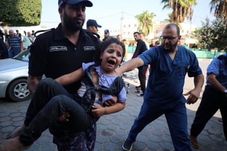 A girl is carried into a hospital after an Israeli raid on Deir al-Balah in Gaza, 14 October.