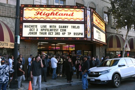 A crowd gathers beneath the marquee of a street-side theater.