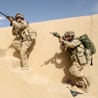 Soldiers aim their rifles during a raid