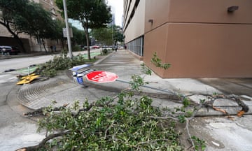 Scattered tree branches and a fallen Stop sign on the pavement in Houston, Texas