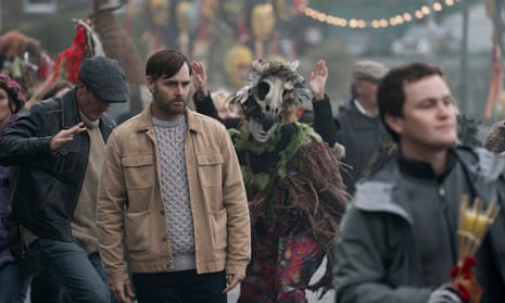 Will Forte as Gilbert Power wonders around a Samhain festival with people in animal masks dancing.