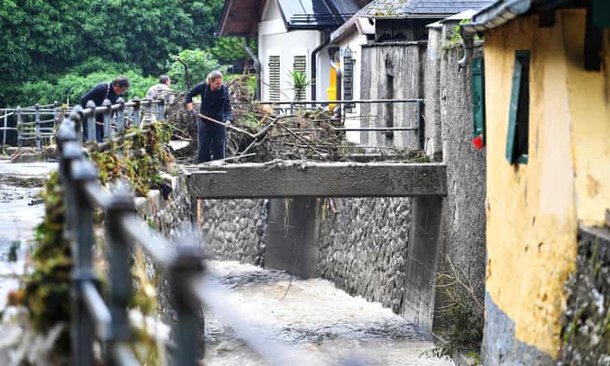 歴史的中心部が浸水した後、男性はオーストリアのハレンで泥とがれきの橋を片付けます。