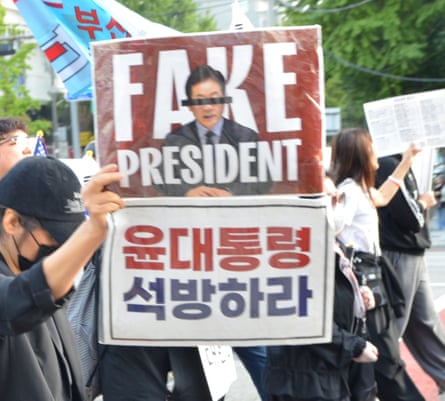Protester holds poster labelling president Lee Jae Myung a ‘fake president’ and calling for the release of impeached predecessor Yoon Suk Yeol.
