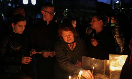 A woman lights a candle as others stand around her